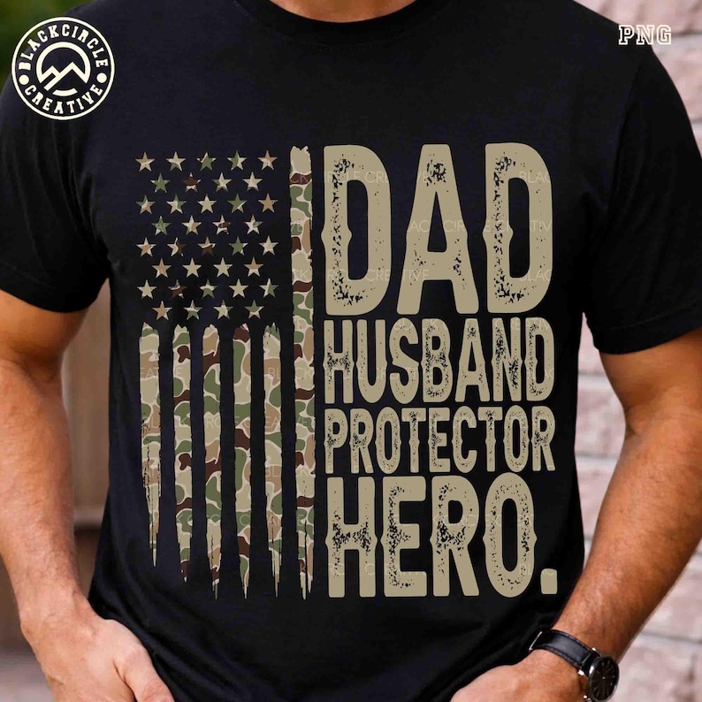 Puede incluir: Camiseta negra con un dise&ntilde;o de bandera americana de camuflaje desgastado. La camiseta presenta las palabras "DAD HUSBAND PROTECTOR HERO" en una fuente beige texturizada. Se ve un reloj en la mu&ntilde;eca.
