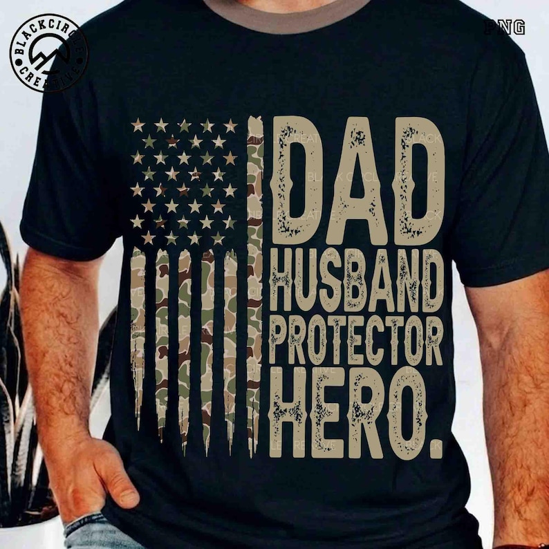 Puede incluir: Camiseta negra con un dise&ntilde;o de bandera estadounidense que incorpora un patr&oacute;n de camuflaje y el texto "DAD, HUSBAND, PROTECTOR, HERO." La impresi&oacute;n tiene un aspecto envejecido. La camiseta tiene cuello redondo y mangas cortas.