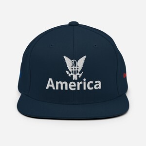 May include: A navy blue baseball cap with a white embroidered American eagle and the word "America" underneath.