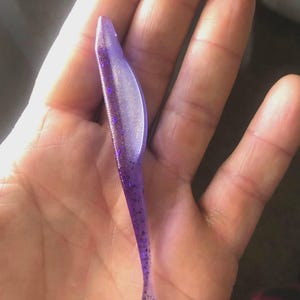 May include: A purple and silver glitter soft plastic fishing lure.