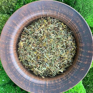May include: A brown ceramic bowl filled with dried herbs and flowers. The bowl is sitting on a bed of green moss.