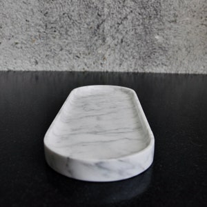 May include: White marble oval tray with a smooth surface and grey veining.