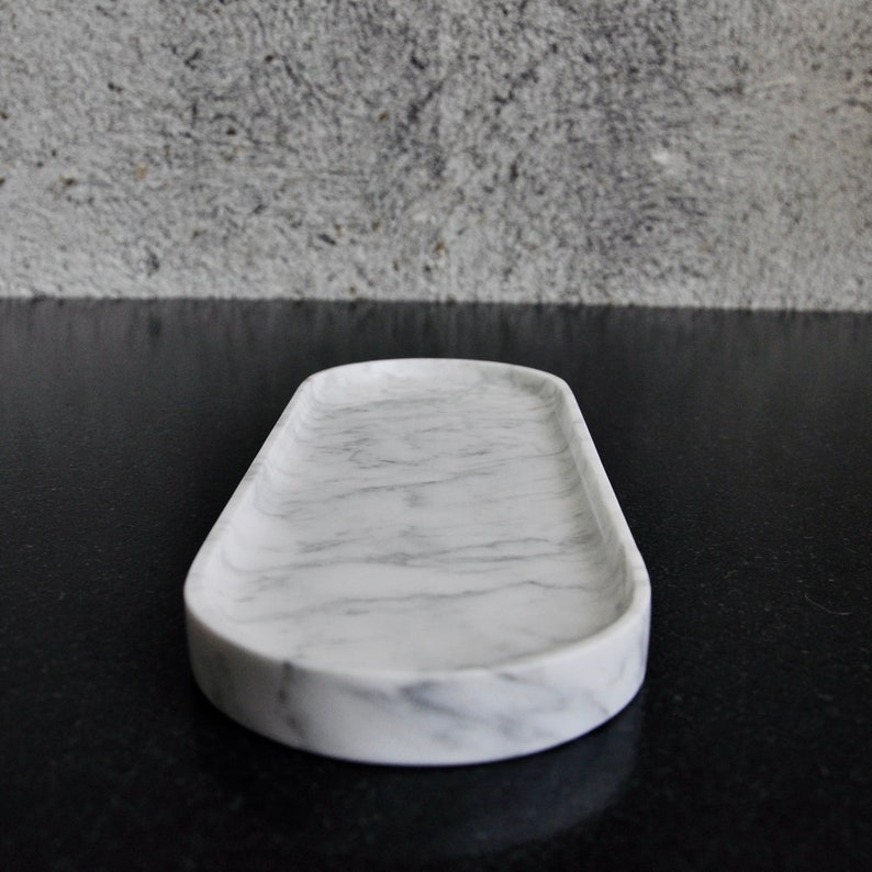 May include: White marble oval tray with a smooth surface and grey veining.