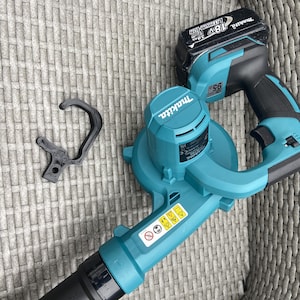 May include: A teal blue and black cordless leaf blower with a black nozzle and a teal blue battery pack that says "18V Lithium-Ion 3.0Ah" and "Makita".
