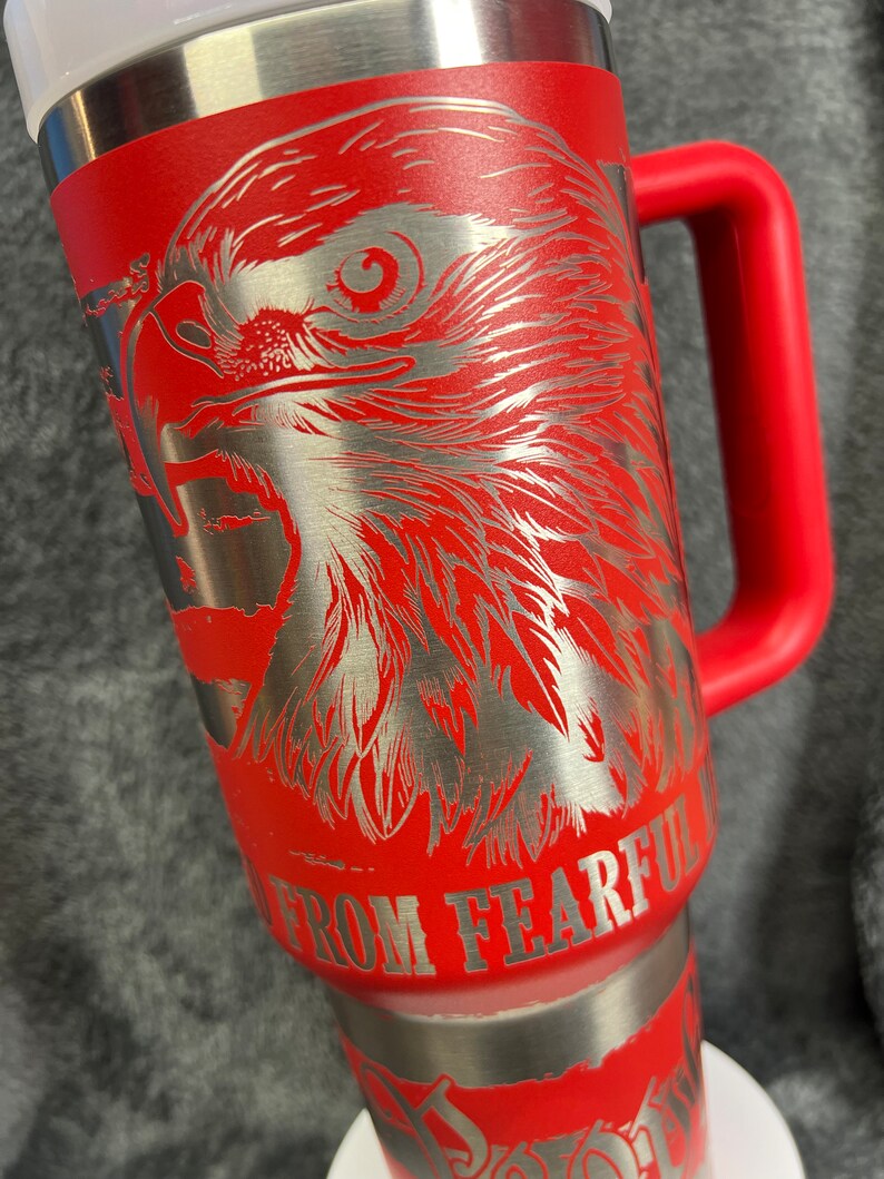 May include: Red stainless steel travel mug with a silver eagle design and the text "Do Not Go Gentle Into That Good Night" and "From Fearful" on the side.