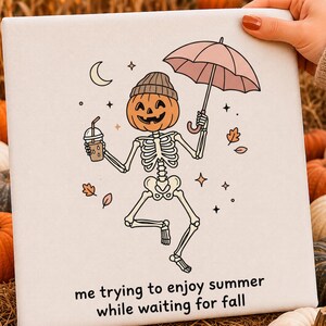 Pode incluir: Uma tela quadrada com um esqueleto de desenho animado com cabeça de abóbora e gorro, segurando um guarda-chuva rosa e um copo de café. O texto diz, me trying to enjoy summer while waiting for fall, rodeado por estrelas e folhas caídas.