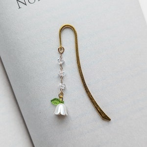 Metal hook bookmark with botanical charm.