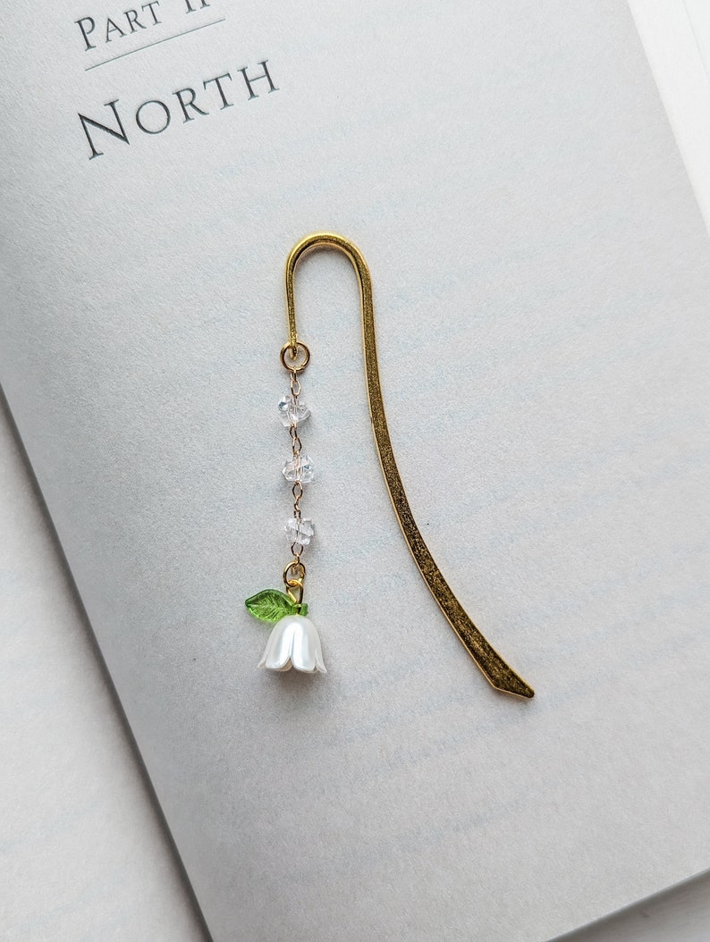 Metal hook bookmark with botanical charm.