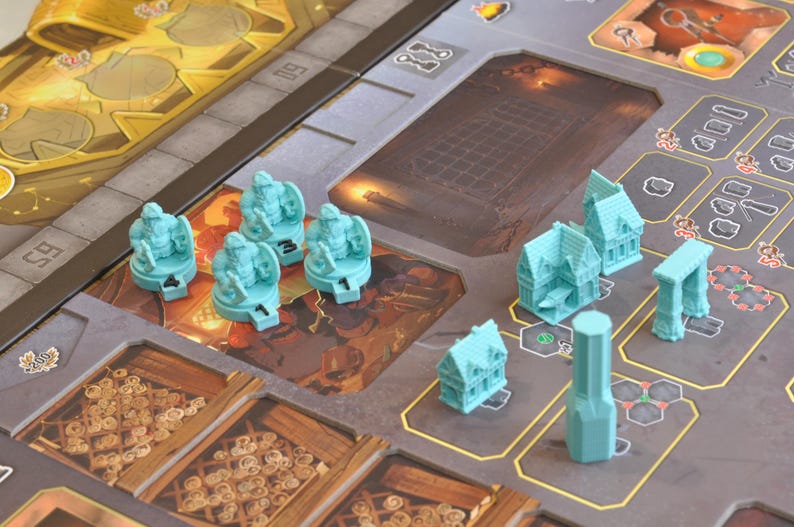 May include: A board game with a detailed game board and several teal-colored game pieces. The pieces include miniature buildings, archways, and figures. The board features various sections with different designs and colors, creating a complex layout.