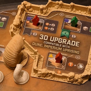 May include: A 3D upgrade set for the Dune: Imperium Uprising board game, featuring tan plastic wall segments, a large sand worm figure, and three smaller sand worm figures. The set includes game board components with text reading 3D UPGRADE COMPATIBLE WITH DUNE: IMPERIUM UPRISING.