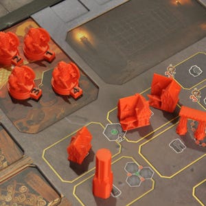 May include: A board game with various orange plastic game pieces, including buildings, towers, and flame-shaped tokens. The game board is brown and gray with a city-like design.