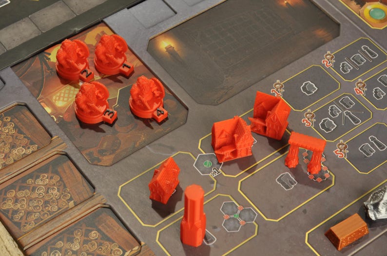 May include: A board game with various orange plastic game pieces, including buildings, towers, and flame-shaped tokens. The game board is brown and gray with a city-like design.