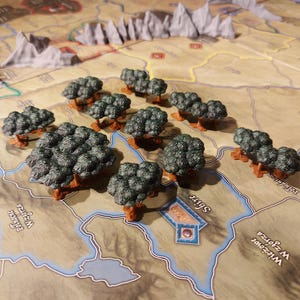 Puede incluir: Un conjunto de 10 árboles en miniatura de color verde con bases marrones. Los árboles están dispuestos en línea sobre una superficie marrón y azul con texto.