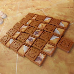 May include: A set of 16 brown tile game pieces with a white and brown desert scene on each tile. The tiles are arranged in a pyramid shape.