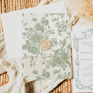 Könnte beinhalten: Hochzeitseinladungs-Set mit einem floralen Design in Salbeigrün auf cremefarbenem Hintergrund. Die Einladung ist mit einem runden Wachssiegel versehen. Eine weitere Karte mit Text ist sichtbar.