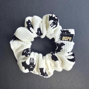 May include: White scrunchie with black bat silhouettes and a black label that says "DOPE"