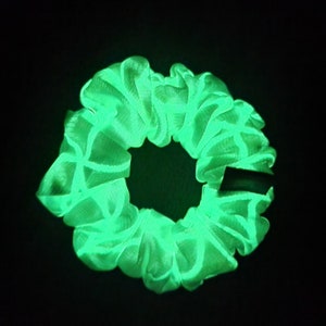 May include: A bright green glow-in-the-dark scrunchie made of soft fabric.