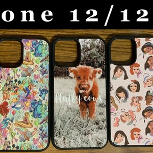 May include: Five different iPhone 12/12 Pro phone cases with various designs. The cases are black with a clear plastic back. The designs include a cartoon character, a cartoon pattern, a highland cow, a pattern of cartoon princesses, and a woman with a dog.