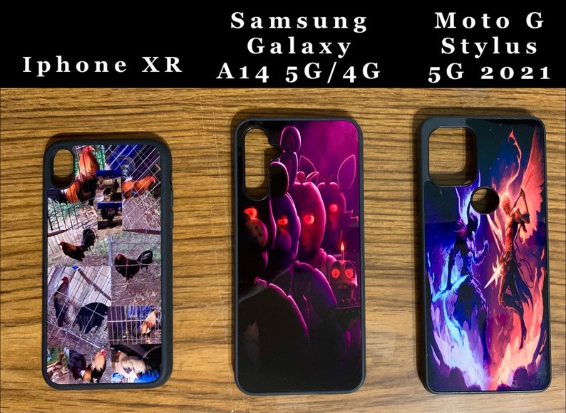 May include: Three different phone cases with various designs. The first case has a collage of chickens in a coop. The second case has a dark purple and black design with a cartoon character. The third case has a blue and red design with a fantasy character.