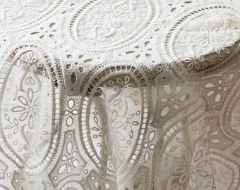 May include: White lace tablecloth with a delicate floral pattern. The tablecloth is circular and features a repeating design of oval-shaped motifs.