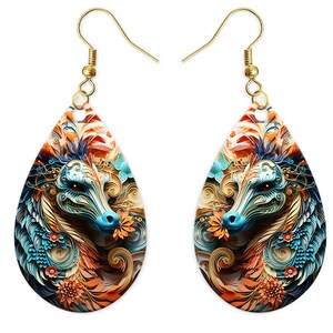 May include: A pair of teardrop-shaped earrings with a colorful, intricate design of a dragon's head with blue, orange, and gold accents. The earrings are made of metal with a gold finish.