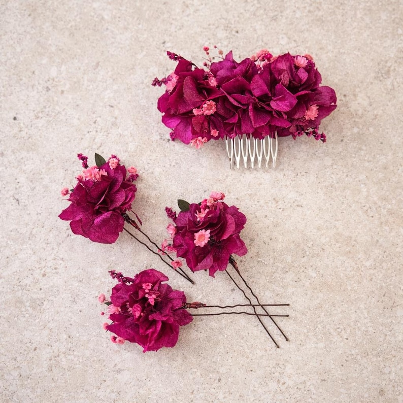 May include: A hair comb and three hair pins featuring deep magenta preserved hydrangea petals and small pink accent flowers. The hair comb has a silver-toned metal base with multiple teeth, while each hair pin has a thin, dark metal wire stem.