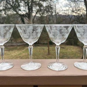 May include: Set of four clear glass stemmed cocktail glasses with an etched floral design.
