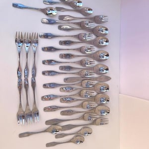 May include: A set of silver flatware, including forks and spoons, arranged in rows on a white background.