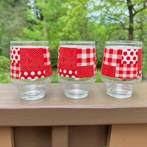 May include: Three clear glass tumblers with red and white checked and polka dot patterns.