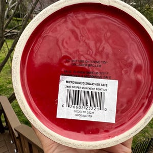 May include: A red ceramic mug with a white rim. The bottom of the mug has a label that reads "MICROWAVE/DISHWASHER SAFE" and "240Z SOUPER MUG EYE OF NEWT A/3". The mug is oven safe to 375&deg;F.