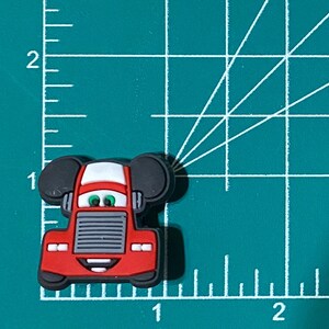 May include: Red cartoon truck with black Mickey Mouse ears. The truck has a white windshield and a gray grill. The truck has a smiling face with green eyes.