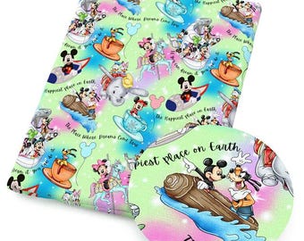 Puede incluir: Una tela verde claro con un patrón colorido con Mickey Mouse, Minnie Mouse, Donald Duck y otros personajes de Disney. El diseño incluye texto que dice "Happiest Place on Earth" y "The Place Where Dreams Come True."