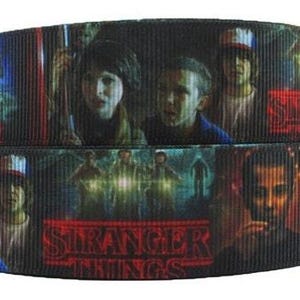 May include: Black and white ribbon with a repeating pattern of characters from the show Stranger Things. The ribbon features the show's logo in red and white.