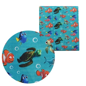 May include: A blue and green fabric with a repeating pattern of cartoon fish and sea turtles. The fish are orange, red, and blue. The turtles are green and brown. The background is a light blue color.