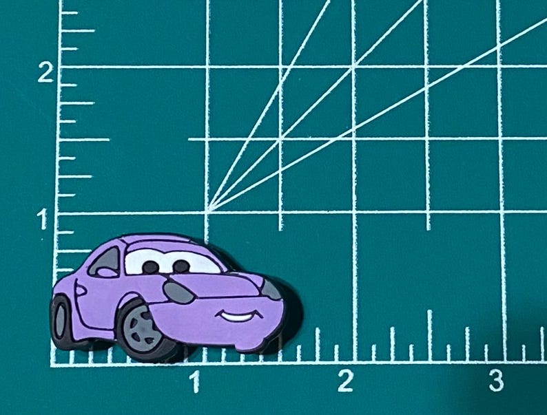 May include: A purple cartoon car with a smiling face. The car has black wheels and a black windscreen.