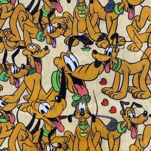 Puede incluir: Patrón repetido con el personaje de dibujos animados Pluto en varias poses. Los perros son principalmente amarillos con detalles en negro, collares verdes y lenguas rosas. El fondo es de color beige claro, con pequeños corazones rojos dispersos.
