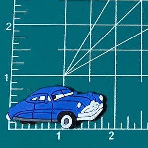 May include: A blue cartoon car with white headlights and a white windscreen. The car has a black stripe along the side and black wheels.