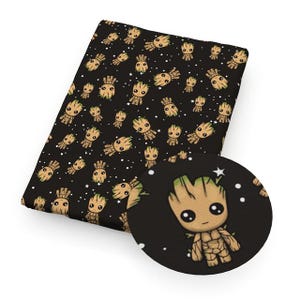 May include: Black fabric featuring a repeating pattern of a cartoon character with a tree-like appearance. The character has a brown body, green accents, and large black eyes. White stars are scattered across the black background.