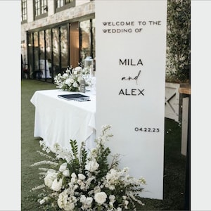 Può includere: Cartello di benvenuto per matrimonio bianco con testo nero che recita "Benvenuti al matrimonio di Mila e Alex 04.22.23".
