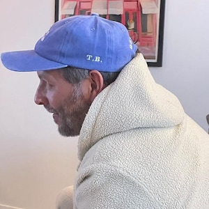 Pu&ograve; includere: Un cappellino da baseball blu con visiera curva. Il cappellino presenta le iniziali "T.B." ricamate in bianco. Il cappellino &egrave; realizzato in un materiale morbido e ha uno stile classico e casual.