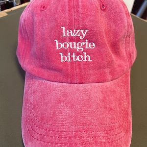 Peut inclure: Casquette de baseball rouge avec l'inscription brodée en blanc "lazy bougie bitch". La casquette a une visière incurvée et un aspect vintage délavé. Le chapeau est fait d'un tissu doux et texturé.