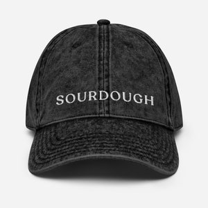 May include: A black vintage washed cotton baseball cap with white embroidered text that reads "SOURDOUGH".