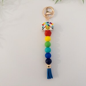 May include: Rainbow beaded keychain with a gold charm featuring a smiley face and the words "Think Happy".