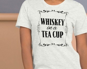 May include: A white t-shirt with a black graphic that says "Whiskey in a Tea Cup" in a decorative font.