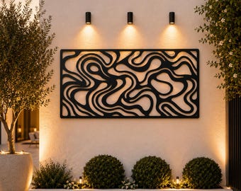 May include: A rectangular black metal wall art panel featuring an intricate, continuous cutout pattern of flowing, organic wavy lines. The piece is mounted on a smooth, light-colored exterior wall, illuminated by three small, warm-toned wall lights.