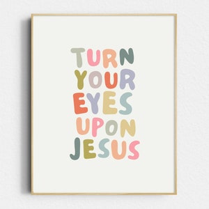May include: A framed art print with the words "TURN YOUR EYES UPON JESUS" in colorful, rounded letters. The text is arranged vertically on a cream-colored background, framed by a light wood border.
