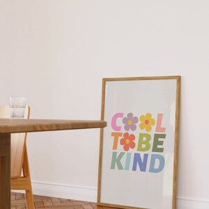 May include: A framed print with a light gray background and the text "COOL TO BE KIND" in colorful letters with flowers between the letters.
