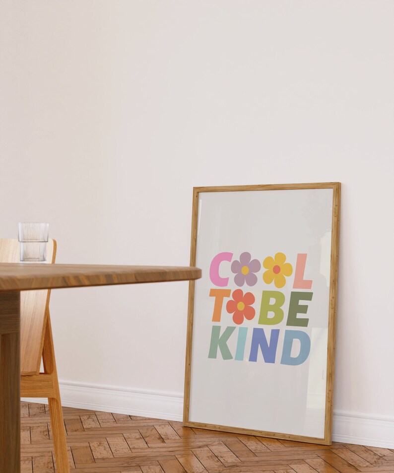May include: A framed print with a light gray background and the text "COOL TO BE KIND" in colorful letters with flowers between the letters.