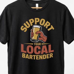 May include: Black t-shirt with the text "SUPPORT YOUR LOCAL BARTENDER" and a graphic of a hand holding a pint of beer. The text is in yellow and red.