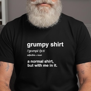 Puede incluir: Camiseta negra con la frase "grumpy shirt" en blanco y una definición. La definición dice: "una camiseta normal, pero conmigo dentro."